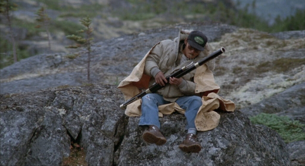 Mike sits on a rock and plays the bassoon